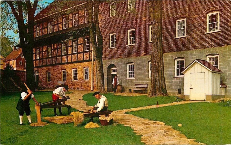 A vintage postcard showing craft demonstrations outside of the Single Brother's House in Old Salem Village. 